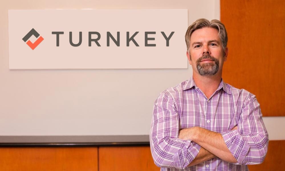 Co-Founder of TurnKey, John Banczak standing in front of TurnKey logo